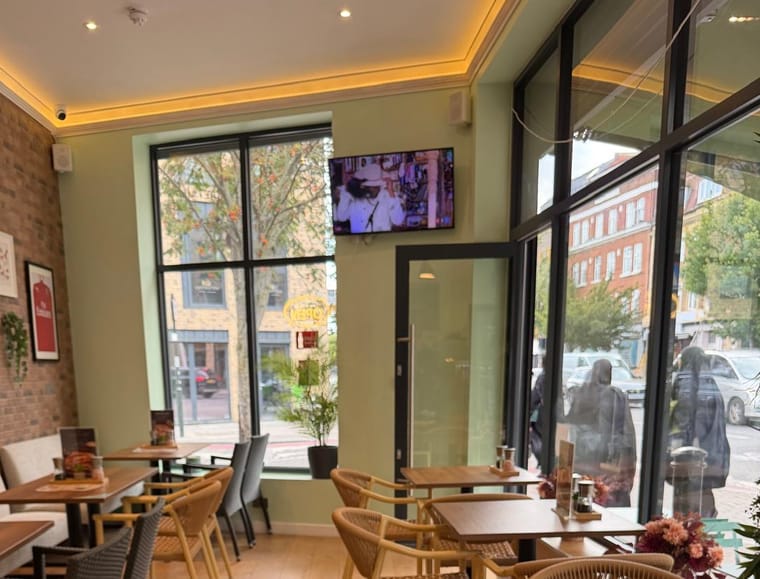 The dining room at Villas Cafe, wicker chairs by tall street-side windows
